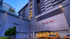 Un hotel moderno con un llamativo letrero 'One-Stop', varios pisos y un estacionamiento con coches.