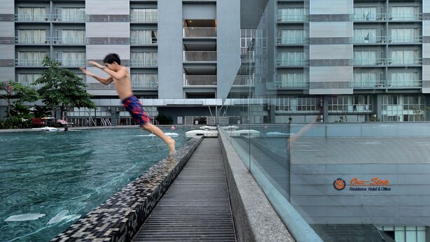 Un hombre salta a una piscina desde un balcón.