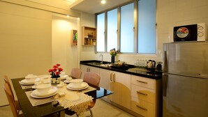 Cocina compacta con zona de comedor, que incluye refrigerador, microondas, lavamanos y armarios de madera.