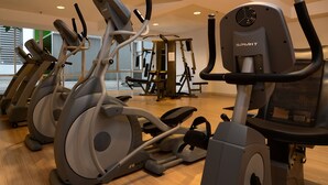 Un gimnasio con varias máquinas de cardio, incluyendo cintas de correr y elípticas, dispuestas en filas.
