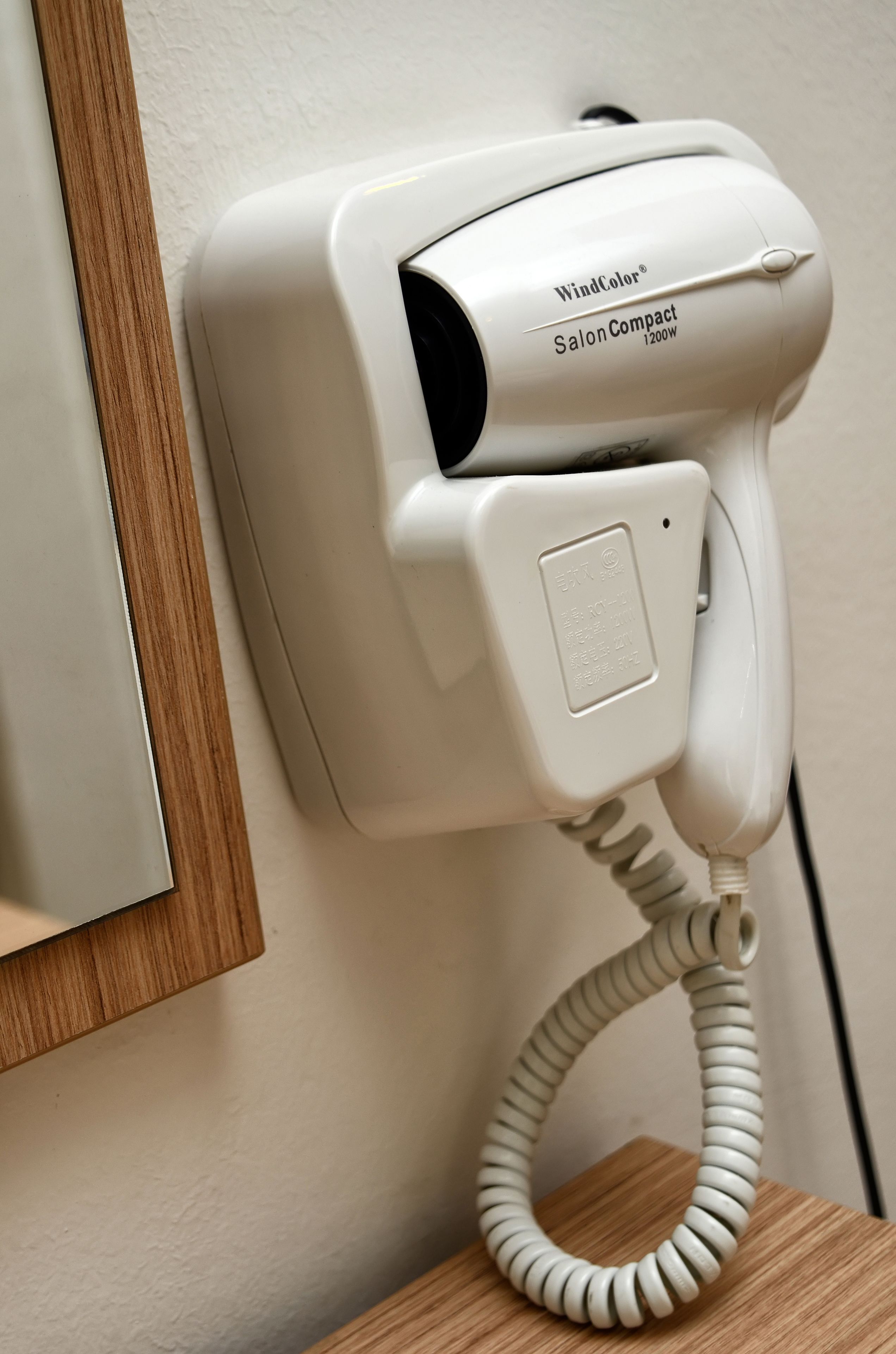 A white hair dryer mounted on a wall, labeled "WindColor® Salon Compact 1200W."