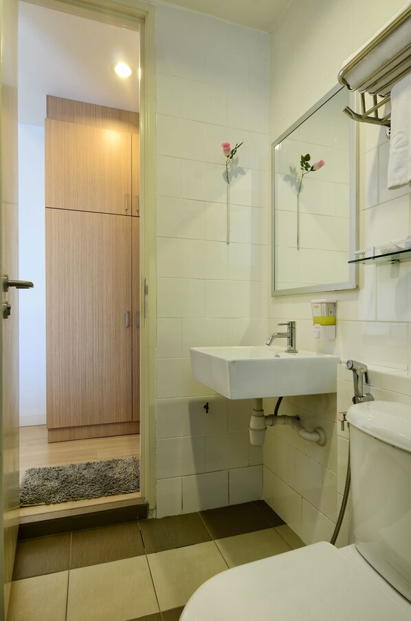 Un baño con lavamanos blanco, espejo, inodoro y puerta de madera.