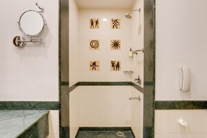 Un baño con espejo, dispensador de papel higiénico y ducha.