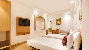 A hotel room with two beds, a TV, a desk with a lamp, and artwork on the walls. - Lemon Tree Hotel, Chandigarh (Chandigarh)