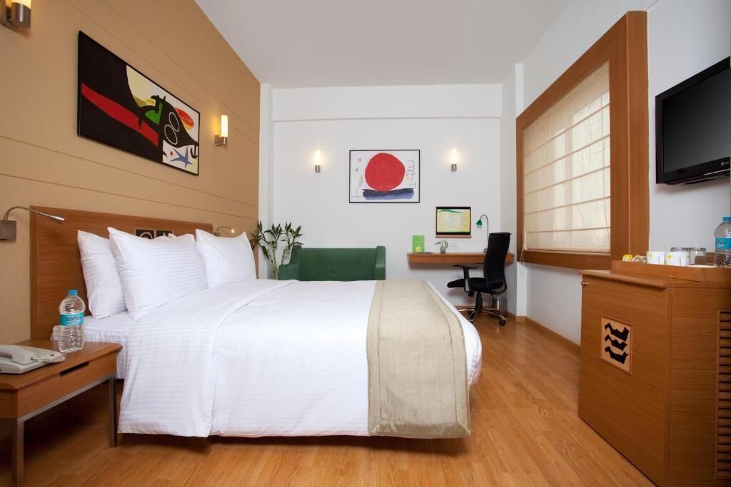 Una habitación de hotel con cama, mesita de noche, escritorio, silla y televisor.