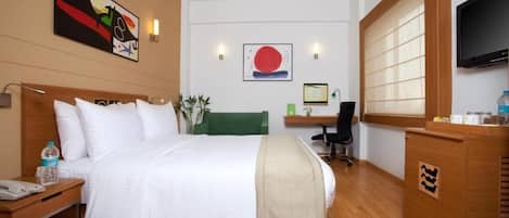 Una habitación de hotel con cama, mesita de noche, escritorio, silla y televisor.