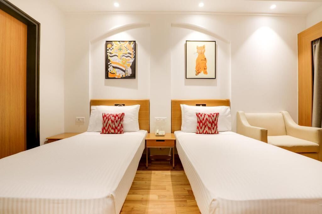 Une chambre d’hôtel avec deux lits, une table de chevet, une chaise et des œuvres d’art accrochées aux murs.