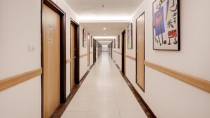 A long, narrow hotel corridor with wooden doors and framed artwork on the walls. - Lemon Tree Hotel, Chandigarh (Chandigarh)