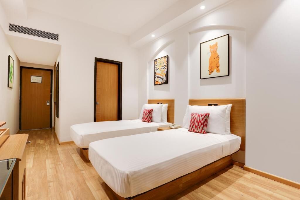A hotel room with two single beds, a wooden headboard, a desk, and a chair.