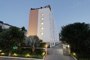 Un hotel moderno con fachada blanca, varios pisos y entrada porticada.