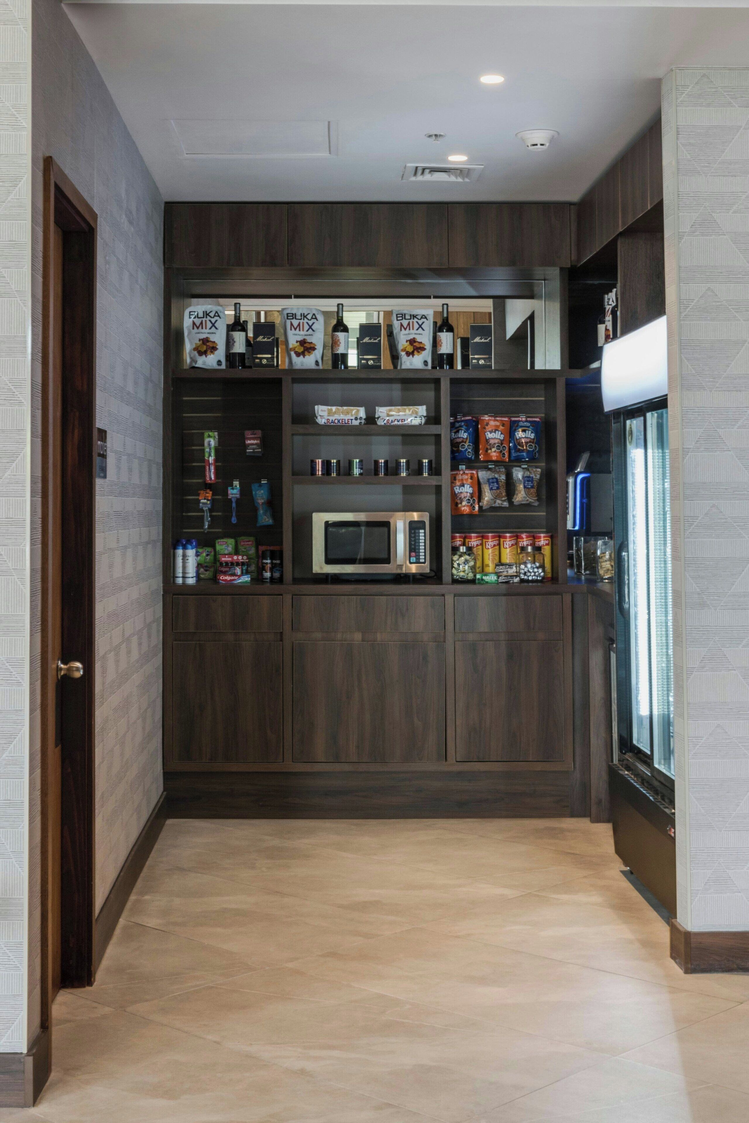 Angolo cottura con mobili in legno scuro, forno a microonde e diversi alimenti.