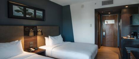 Habitación de hotel con dos camas, una kitchenette pequeña y un cuadro enmarcado en la pared.