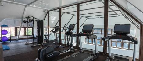 A gym with treadmills, elliptical machines, and exercise balls.
