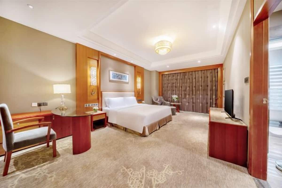 Une chambre d’hôtel équipée d’un lit, d’un bureau, d’une chaise, d’une télévision et d’une armoire en bois.