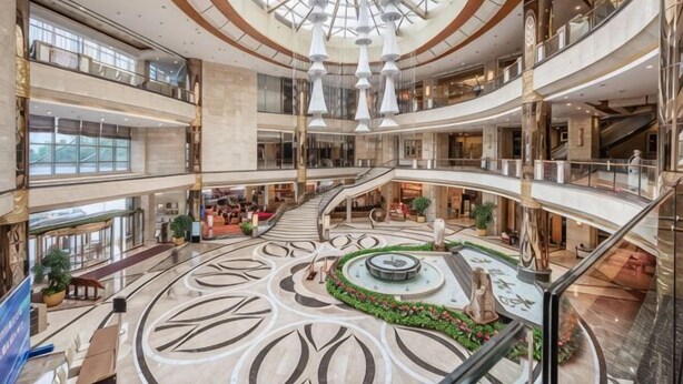Un atrium d'ambients múltiples amb un jardí circular central, diversos pisos i una àmplia escalinata.