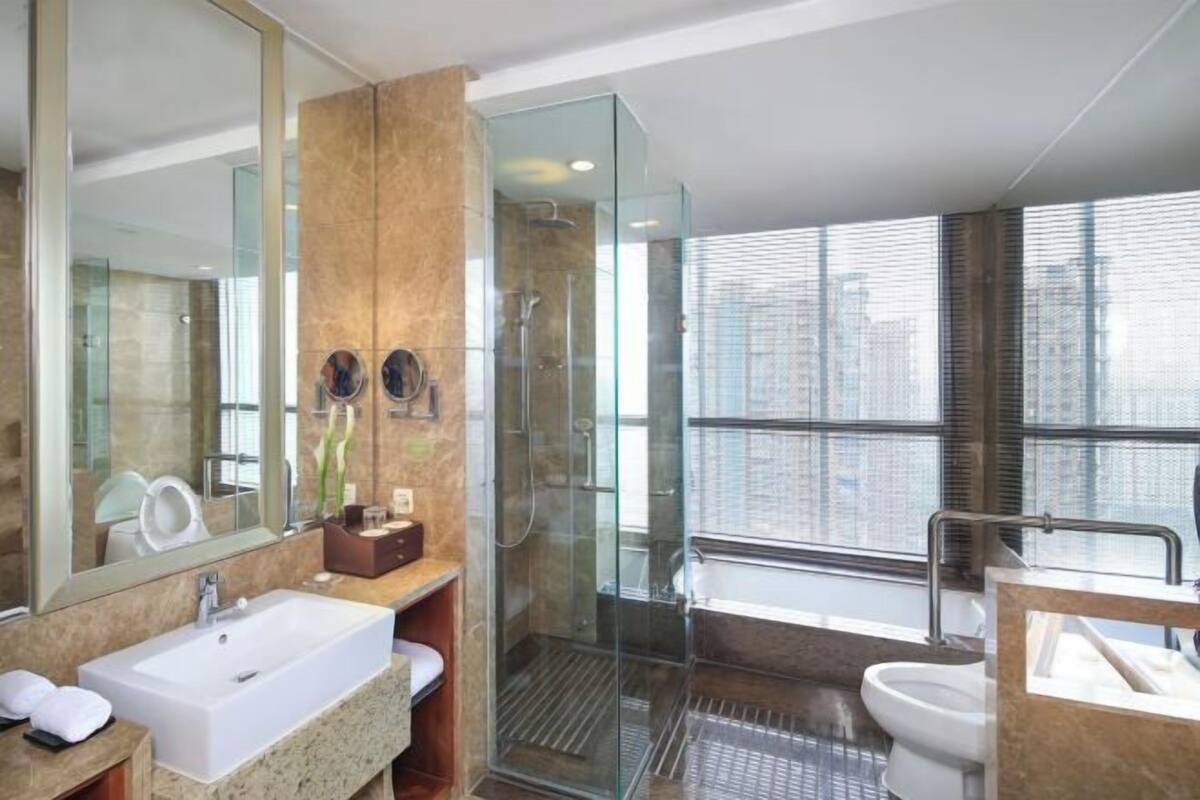 Une salle de bain moderne avec un grand miroir, un lavabo, une cabine de douche et des toilettes.