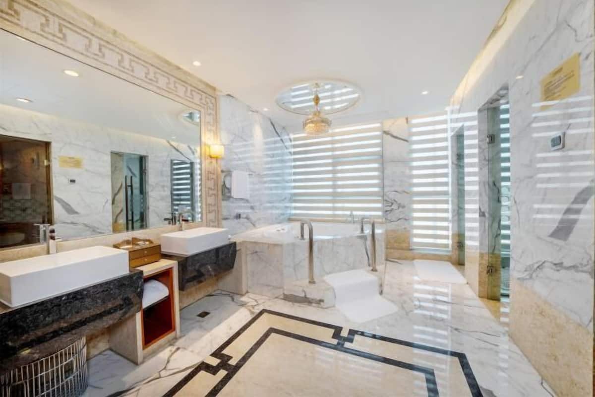 Une salle de bain luxueuse avec un sol en marbre, un grand miroir et un design moderne.