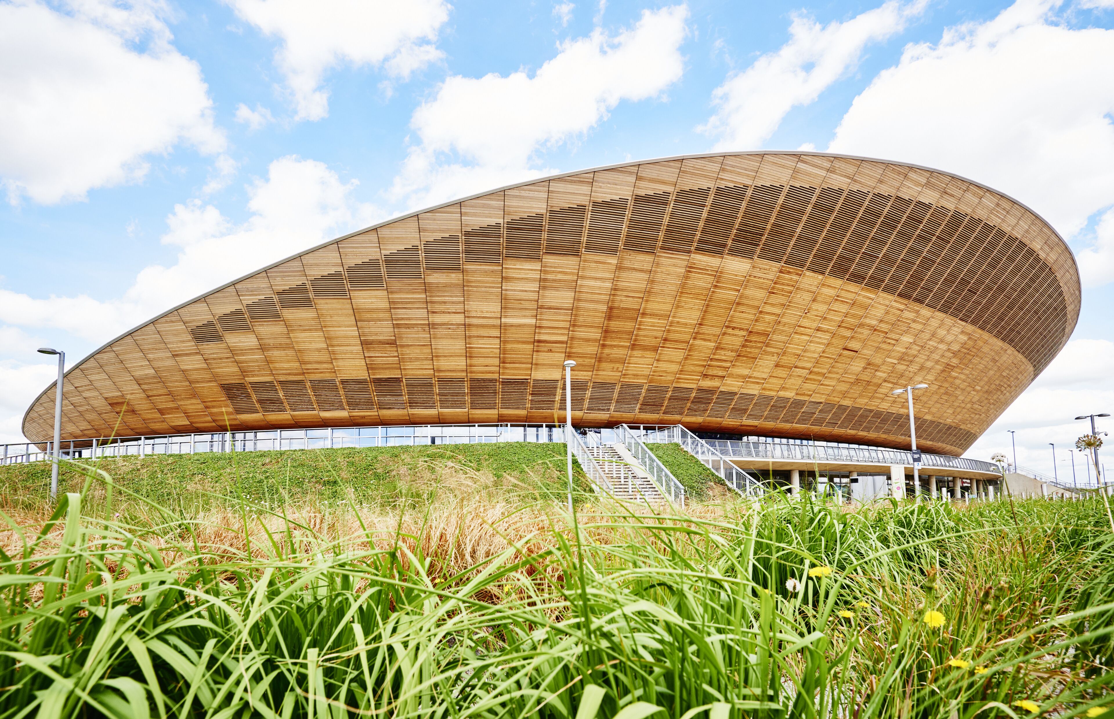 Een modern stadion met een opvallend gebogen dak en een trap naar de ingang.