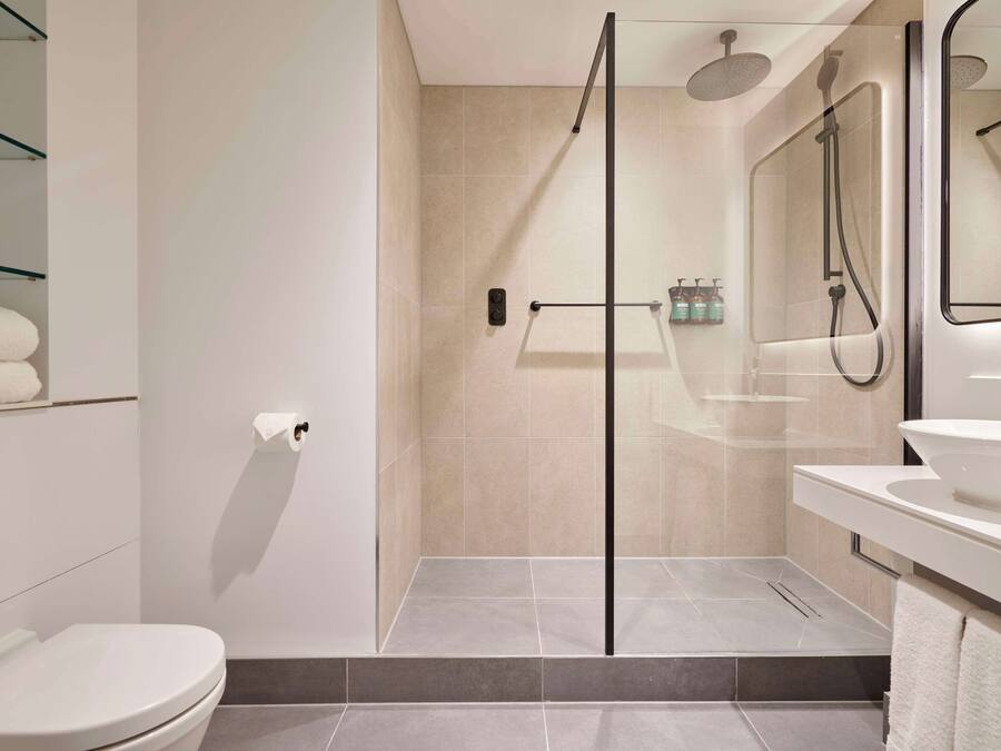 A modern bathroom with a glass-enclosed shower, a white sink, and a toilet.