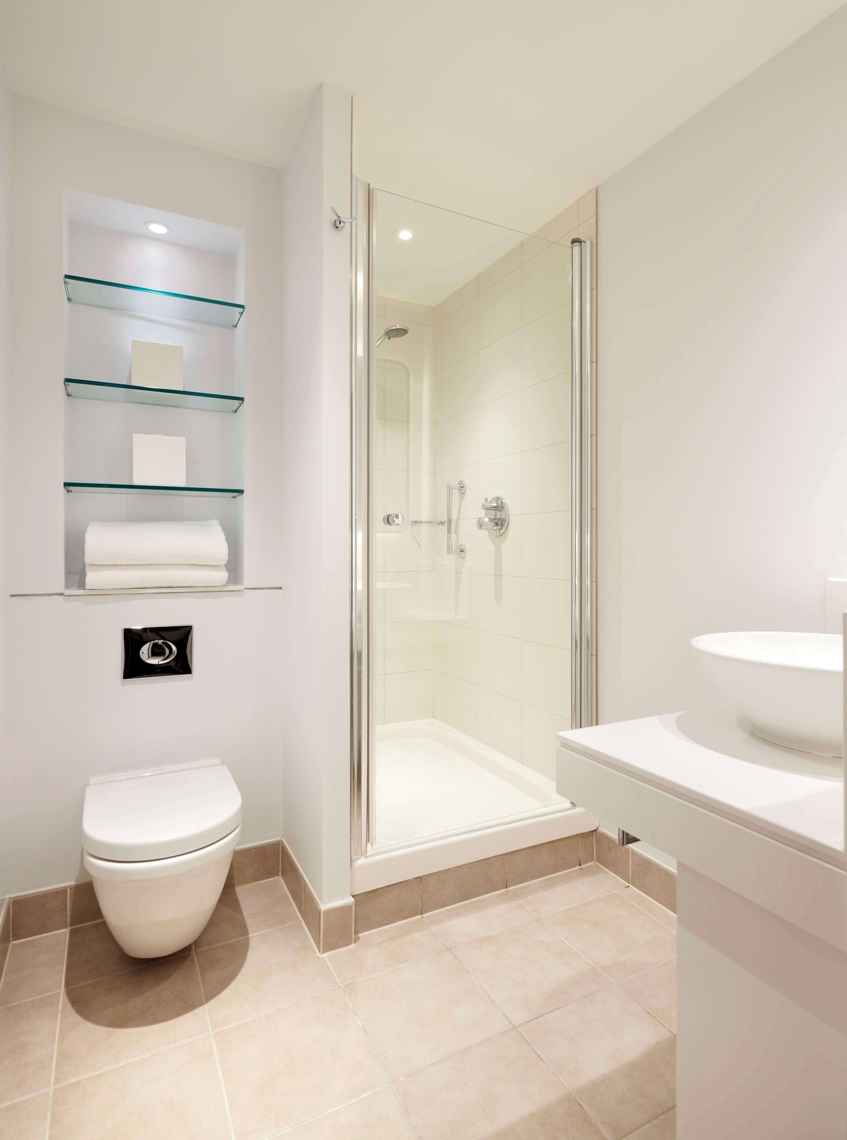 A modern bathroom with a glass shower enclosure, a toilet, and a sink.