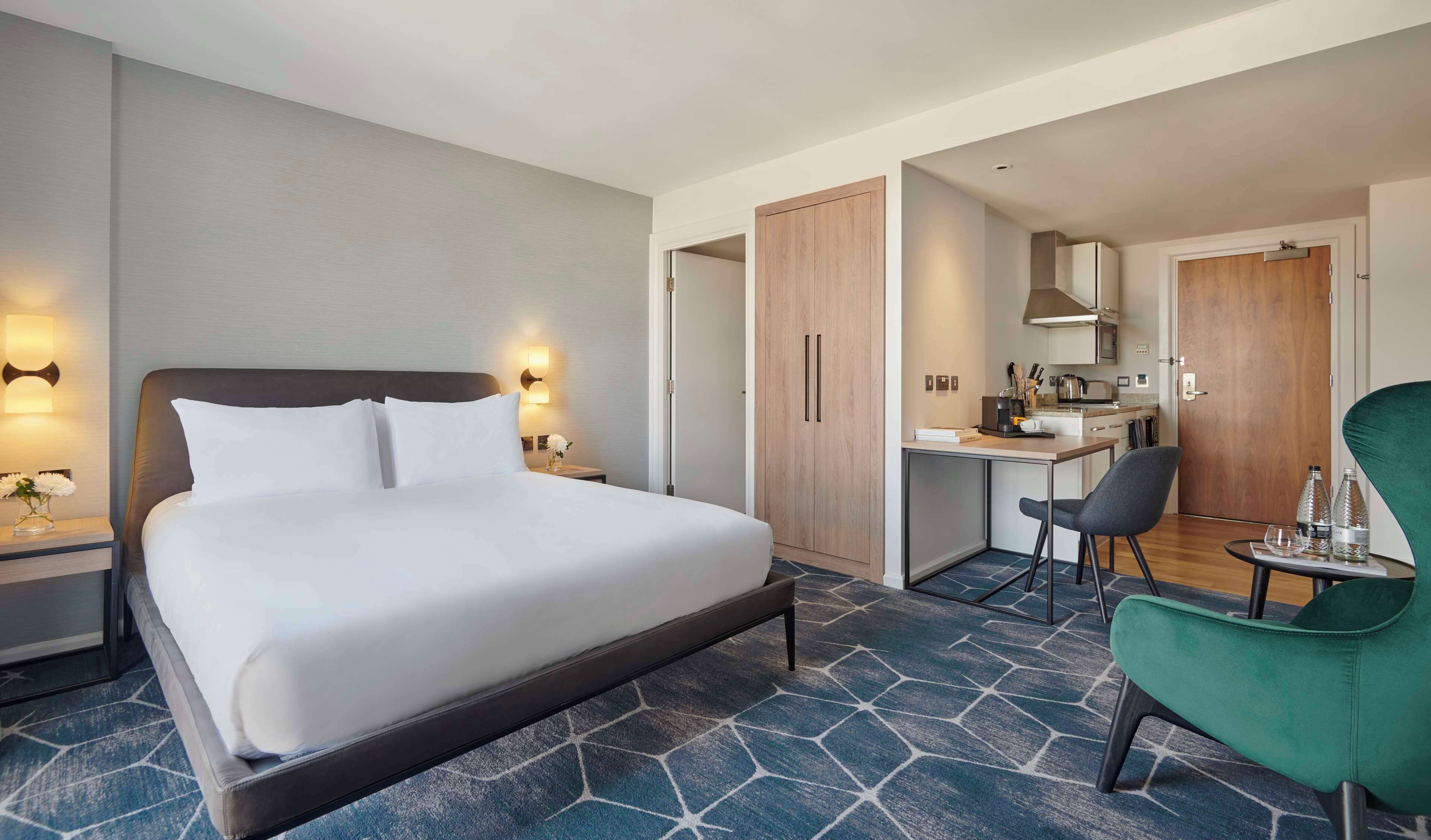 Une chambre d’hôtel équipée d’un lit, d’un bureau, d’une chaise et d’une kitchenette.