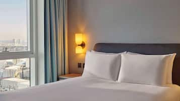 A hotel room with a large bed, a nightstand with a lamp, and a view of the city through the window.