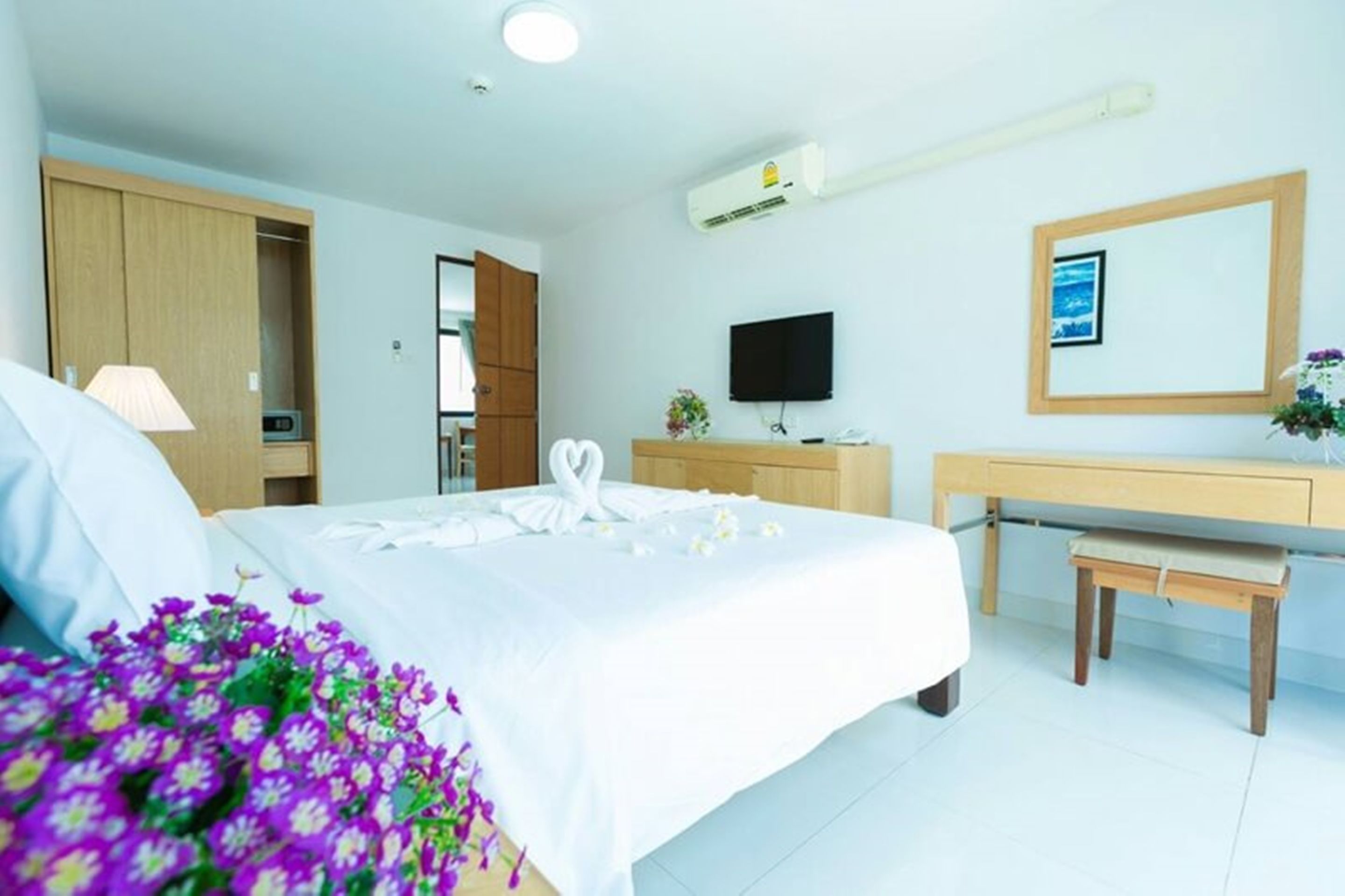 A hotel room with a bed, a desk, a TV, and a wardrobe.
