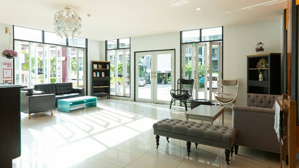 A spacious lobby with a modern design, featuring a large seating area with a sofa, ottoman, and chairs, a coffee table, and a bookshelf. - Neo Hotel Pattaya (Pattaya)