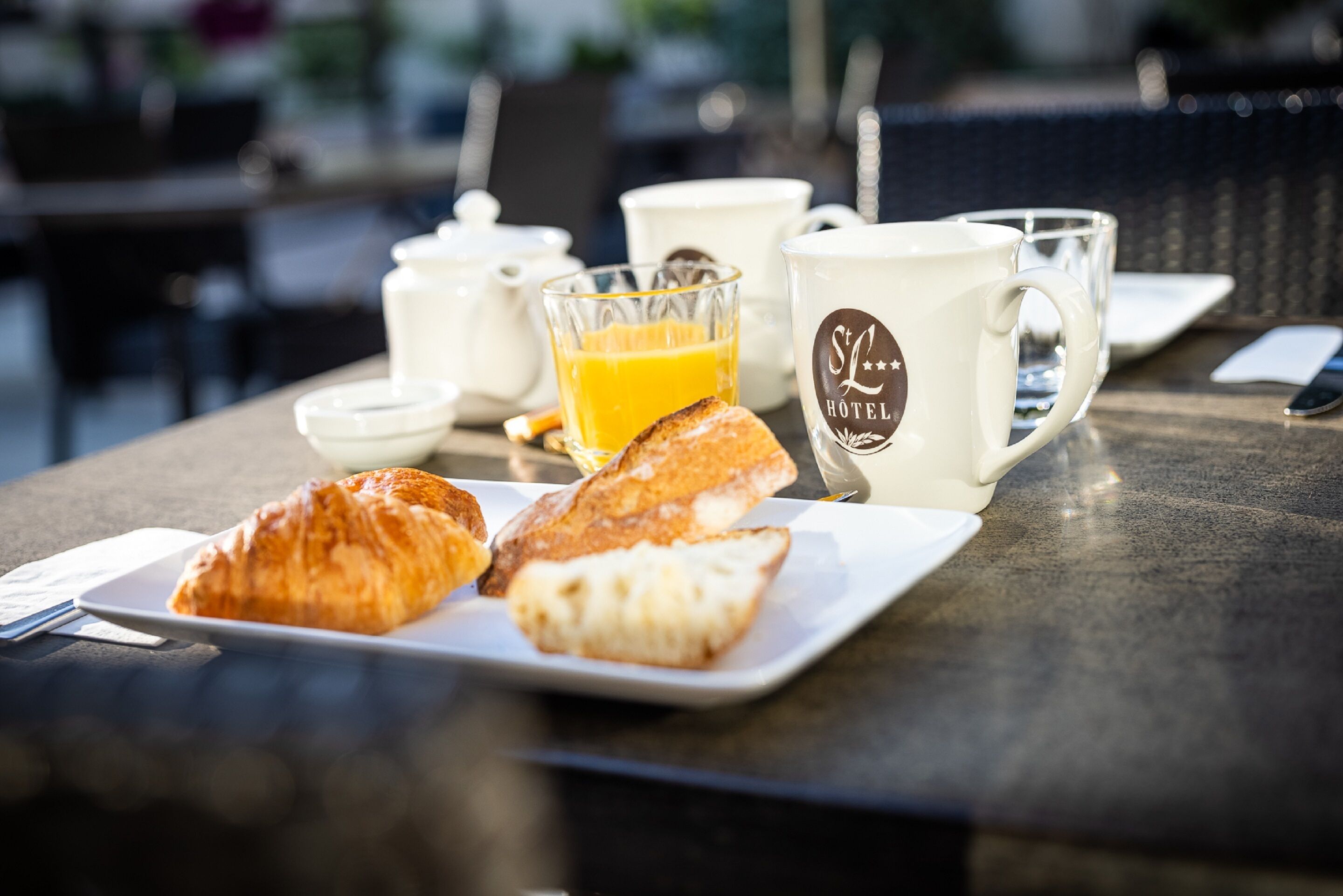 A breakfast setting with croissants, orange juice, and a coffee mug on a table.
