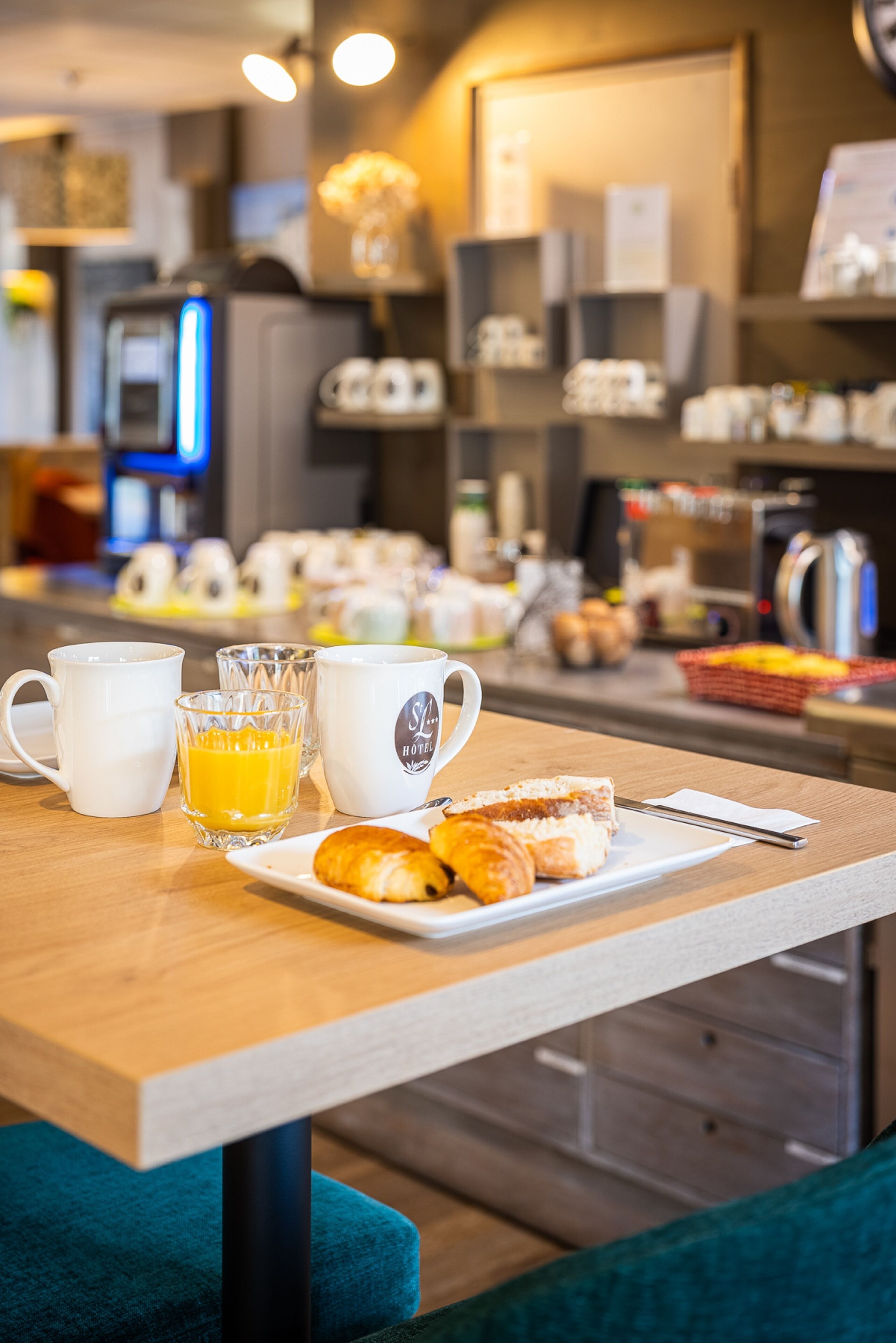 Una presentación para el desayuno con tazas de café, un vaso de jugo de naranja y pasteles sobre una mesa en una habitación de hotel.