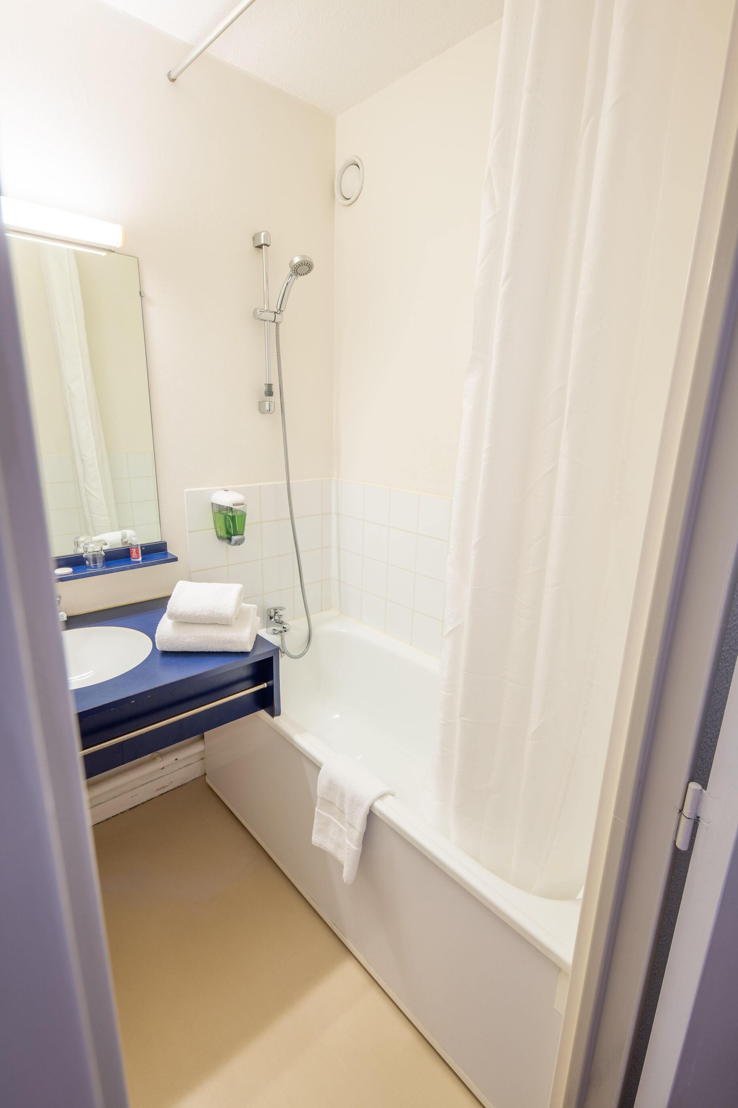 Un bany amb banyera, un lavabo i un mirall.