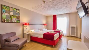 A hotel room with a bed, a sofa, a TV, and a wall art piece.