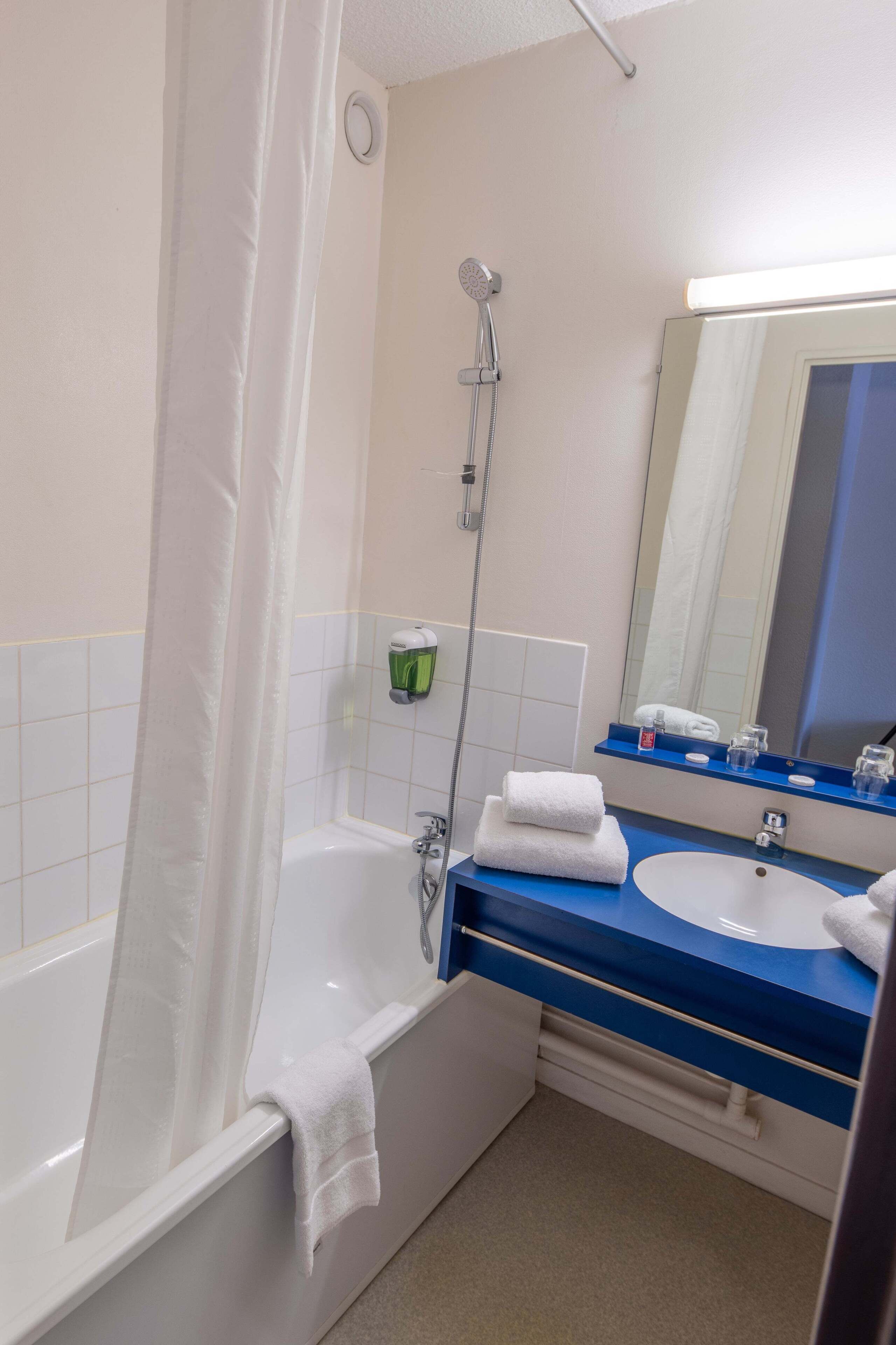 Ein Badezimmer mit Badewanne, Dusche, Waschbecken und Spiegel.