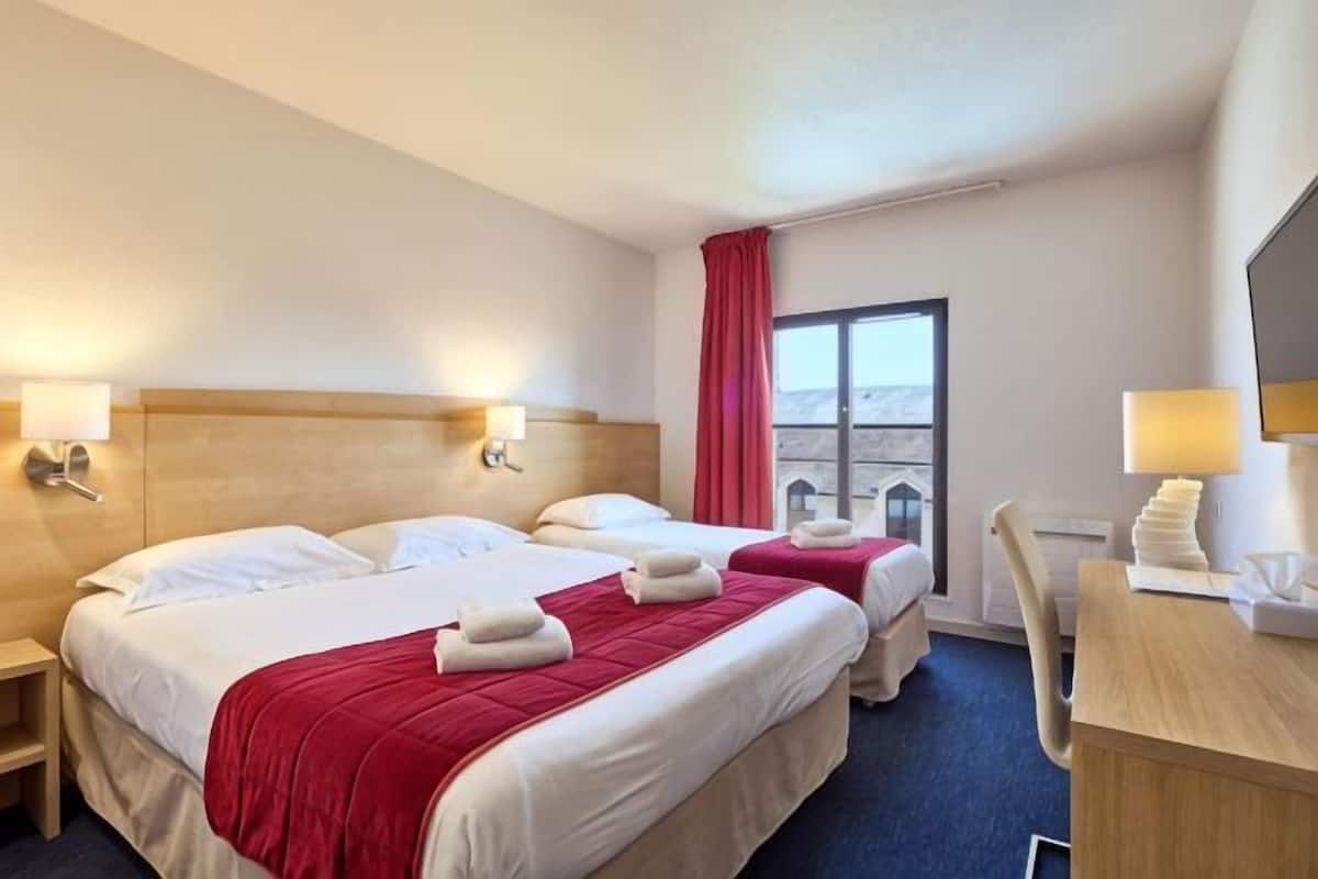 A hotel room with two beds, a desk, a chair, a window with a view, and a red curtain.