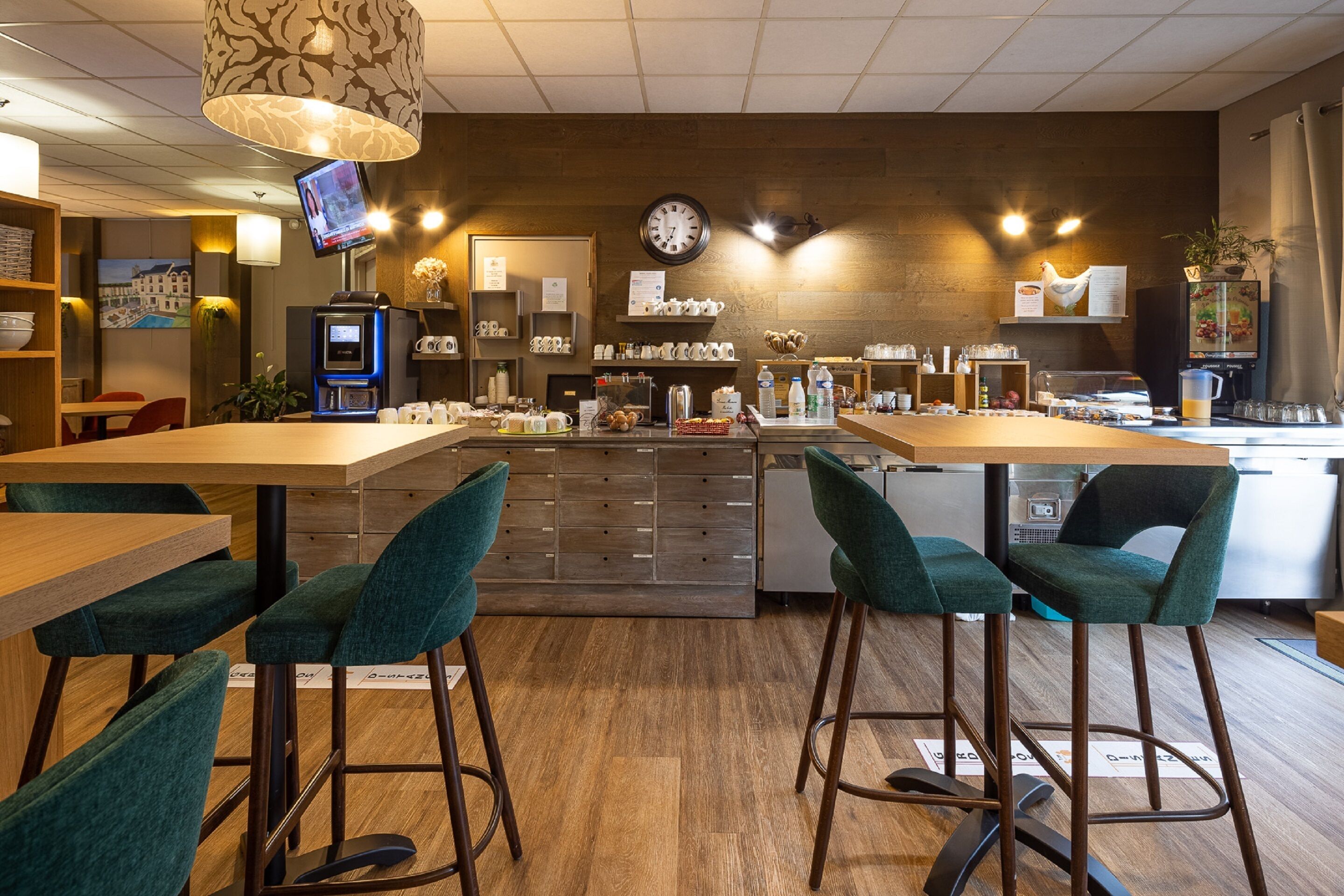 Un café moderno con taburetes, una máquina de café y una pantalla de televisión.