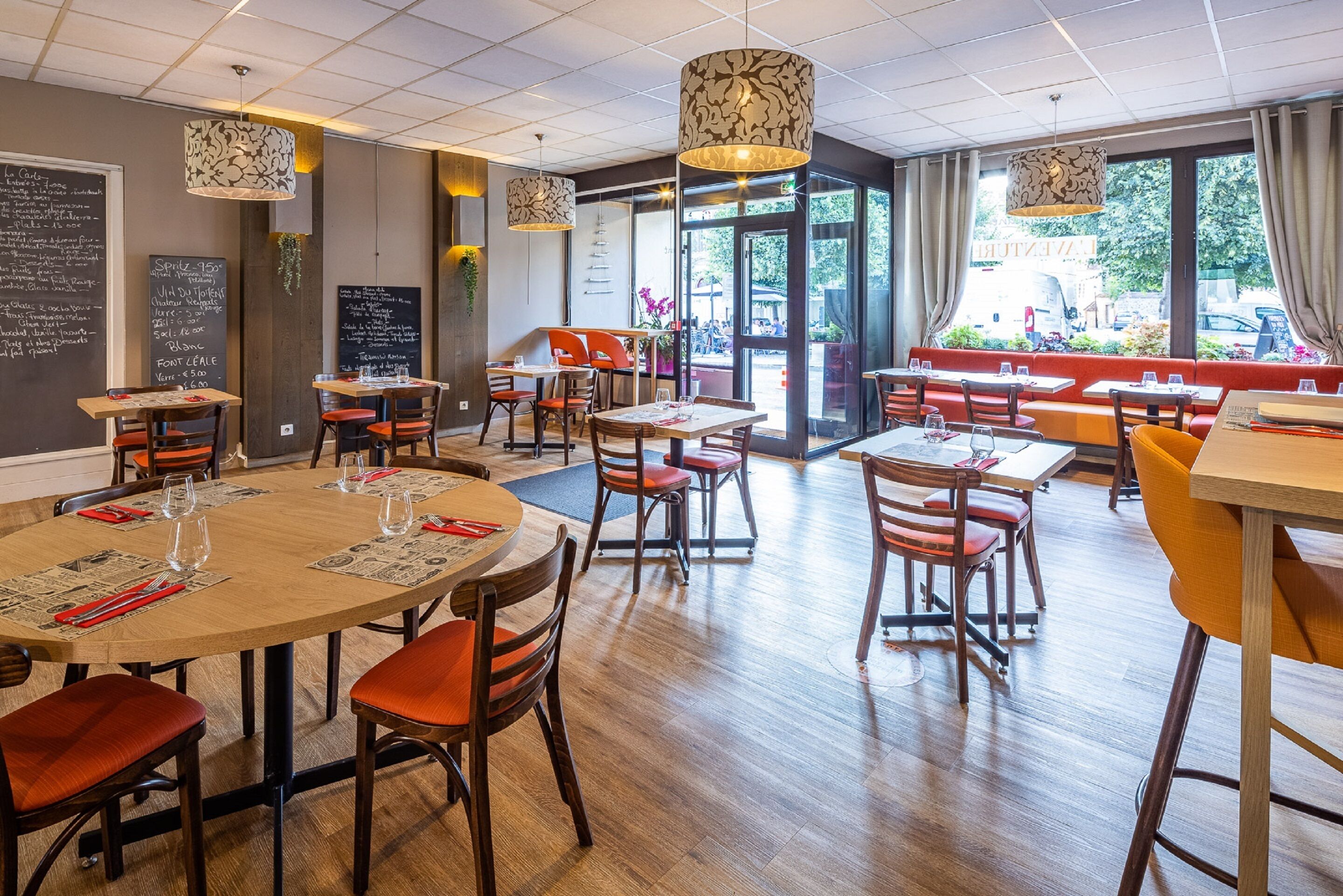 Ein Restaurant mit runden Tischen, roten und gelben Stühlen und hängenden Lampen.