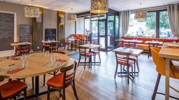 Ein Restaurant mit runden Tischen, roten und gelben Stühlen und hängenden Lampen.