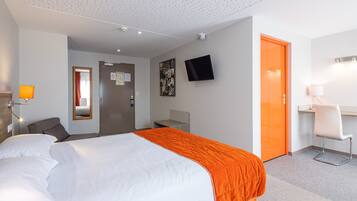 Una habitación de hotel con cama, escritorio, silla, televisión y puerta.