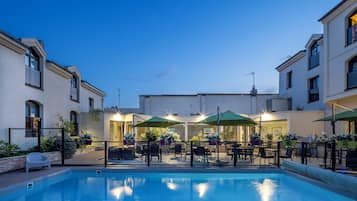 Una piscina al aire libre de temporada, sombrillas