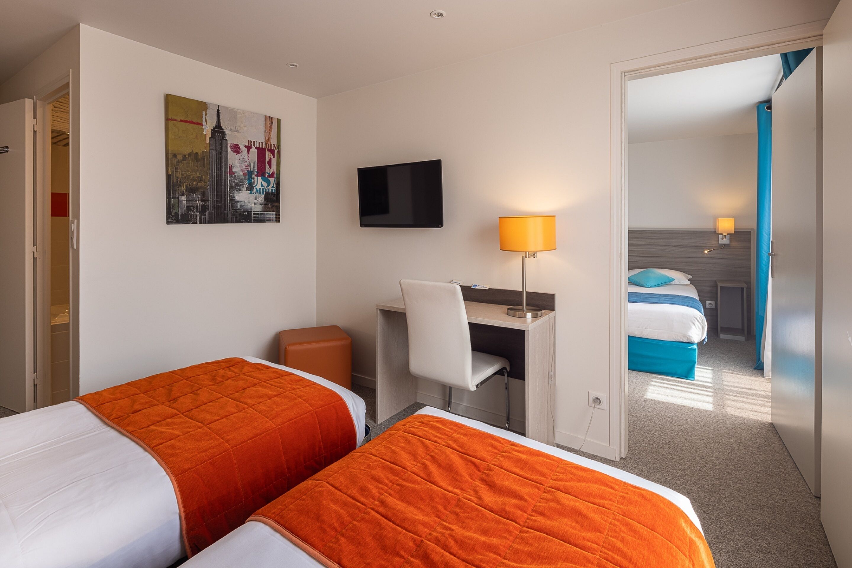 Une chambre d’hôtel avec deux lits, un bureau avec une chaise, une télévision et un tableau au mur.