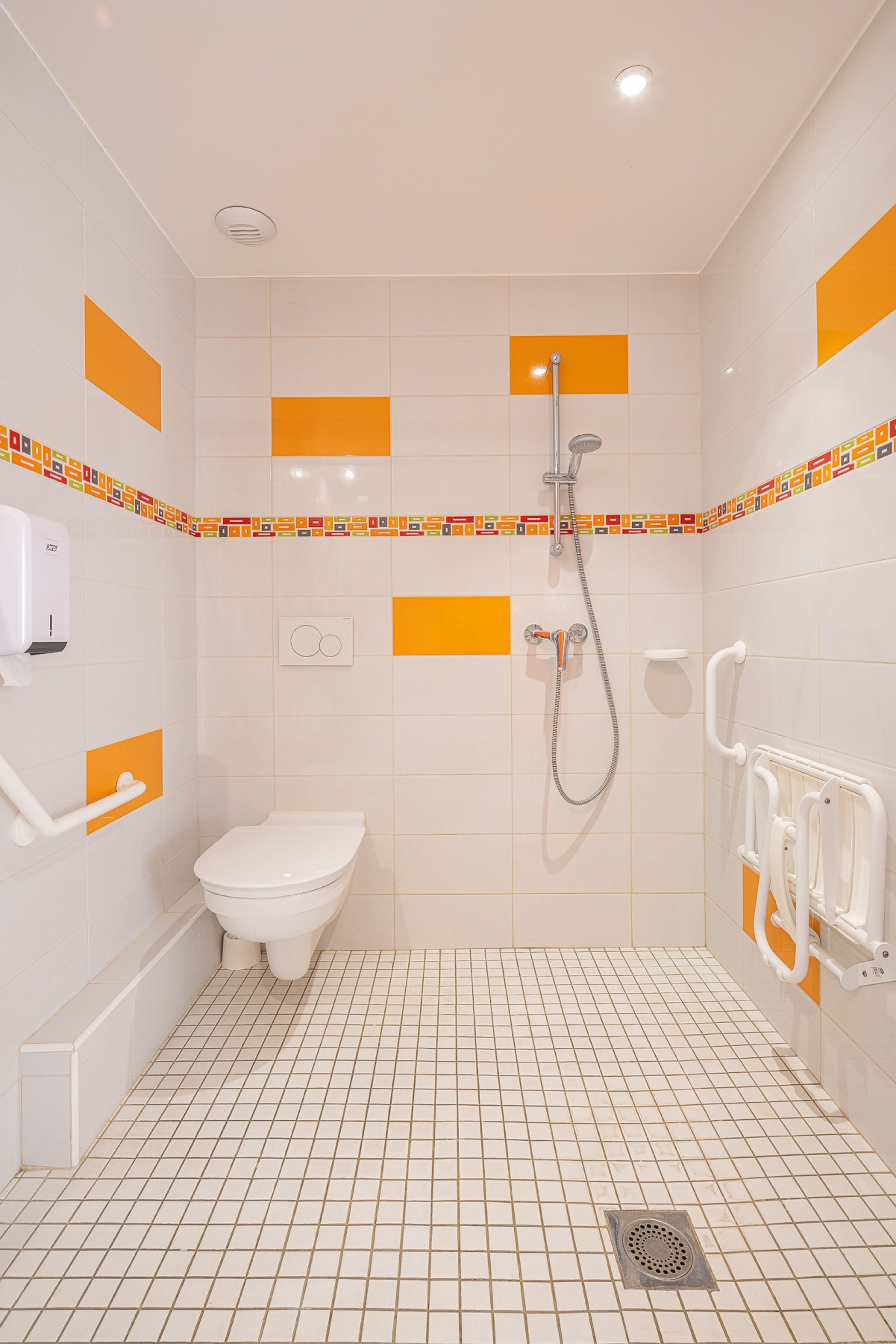 Et badeværelse med toilet, bruser og hårtørrer.
