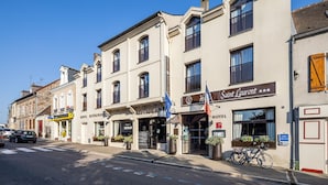 Une rangée de bâtiments abritant un restaurant, un hôtel et d’autres commerces, le tout situé dans une rue ensoleillée.