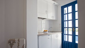 Une cuisine avec des meubles blancs, une porte bleue et une chaise à motifs floraux.