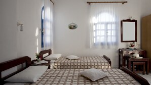 Une chambre avec deux lits, un bureau en bois, un miroir et une fenêtre avec des rideaux.