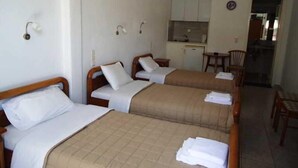 A room with two beds, a kitchenette, and a dining area. - Pension Romantika (Mykonos)