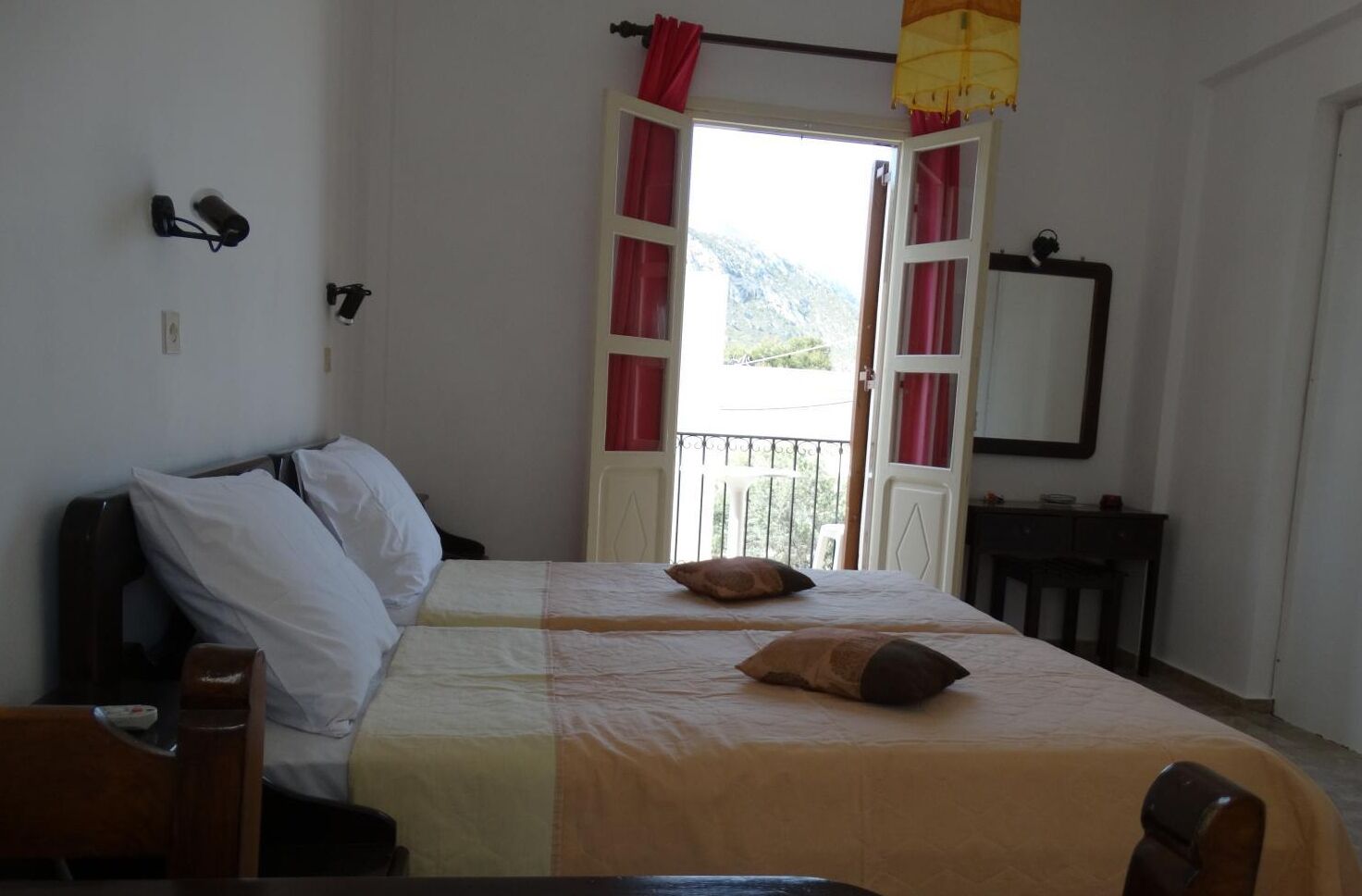 Un dormitorio con cama, una mesita de noche, una silla, una ventana con cortinas y vistas al exterior.