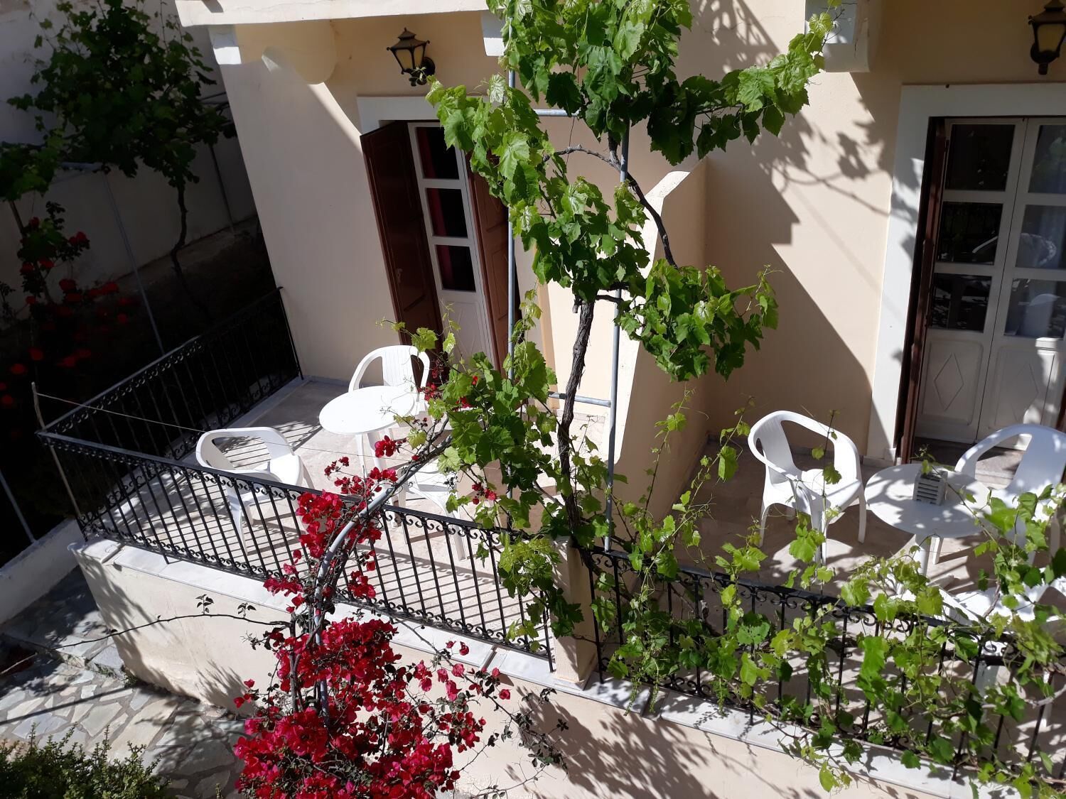 A balcony with white chairs, a small table, and a metal railing.