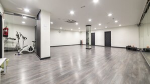Una habitación amplia con suelo de madera gris, una pared de vidrio y una fila de puertas negras.
