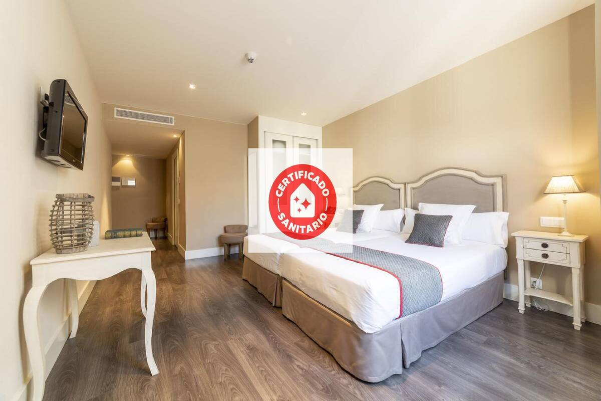 A hotel room with a bed, bedside tables, a TV, and a certificate of sanitation.