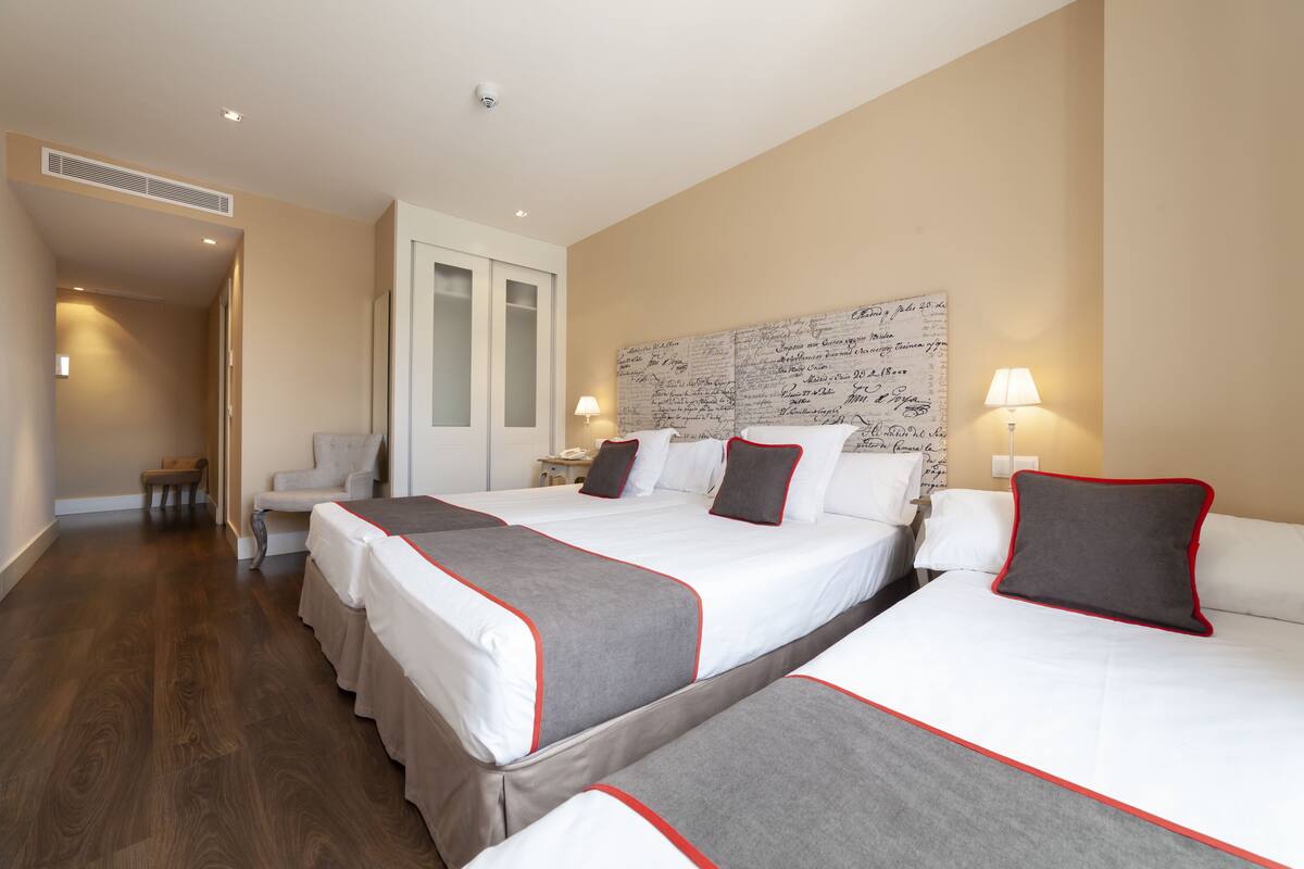 A hotel room with two beds, a desk, a chair, and a wall with writing.